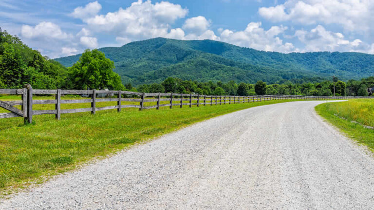 Curved country road with wooden fence and mountains