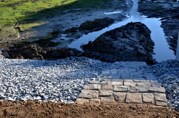 Textured riverbed with water, stones, and concrete steps